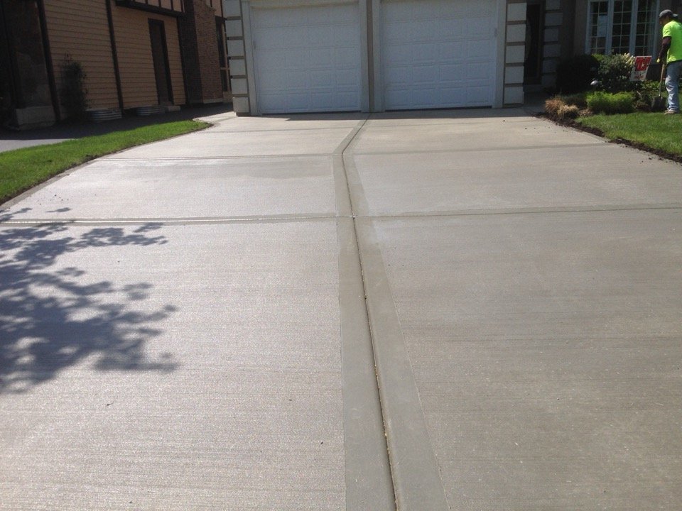 Finished concrete driveway with joint lines leading to a residential garage