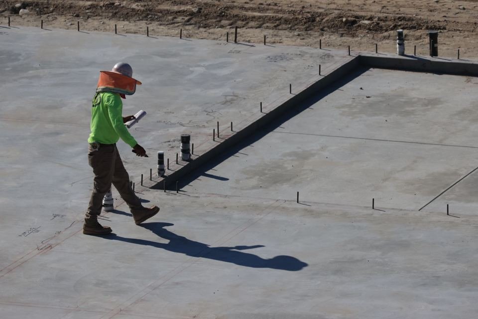 Representative concrete slab with edge details, penetrations and a person reviewing a plan